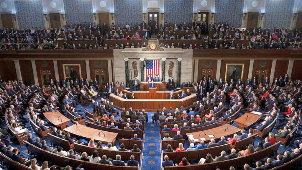 A wide, elevated view of a crowded United States House of Representatives chamber during a congressional session.