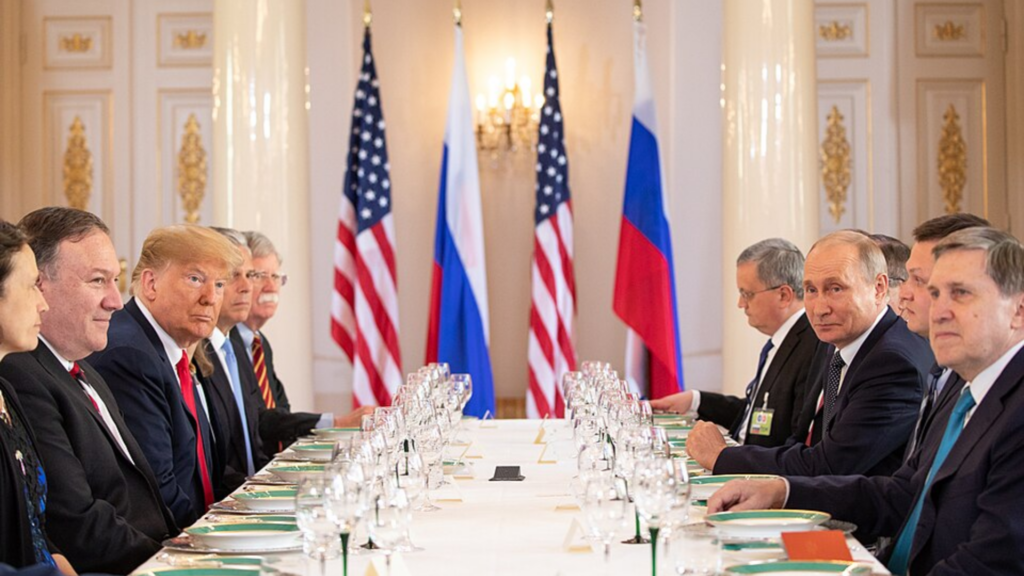Donald Trump, Vladimir Putin, and their respective delegations facing each other across a long table during a formal bilateral meeting.