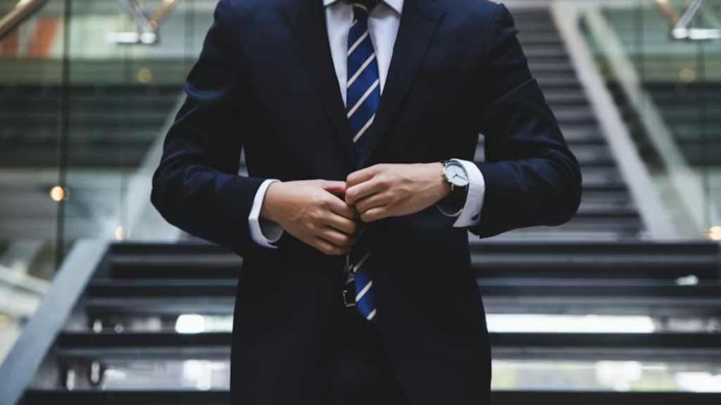 Business executive adjusting suit jacket while standing in office building atrium.