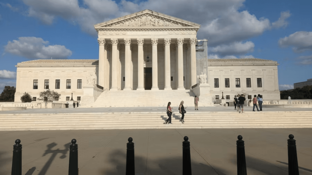 A wide-angle shot of the U.S. Supreme Court Building in Washington, D.C., under a bright, cloudy afternoon sky.