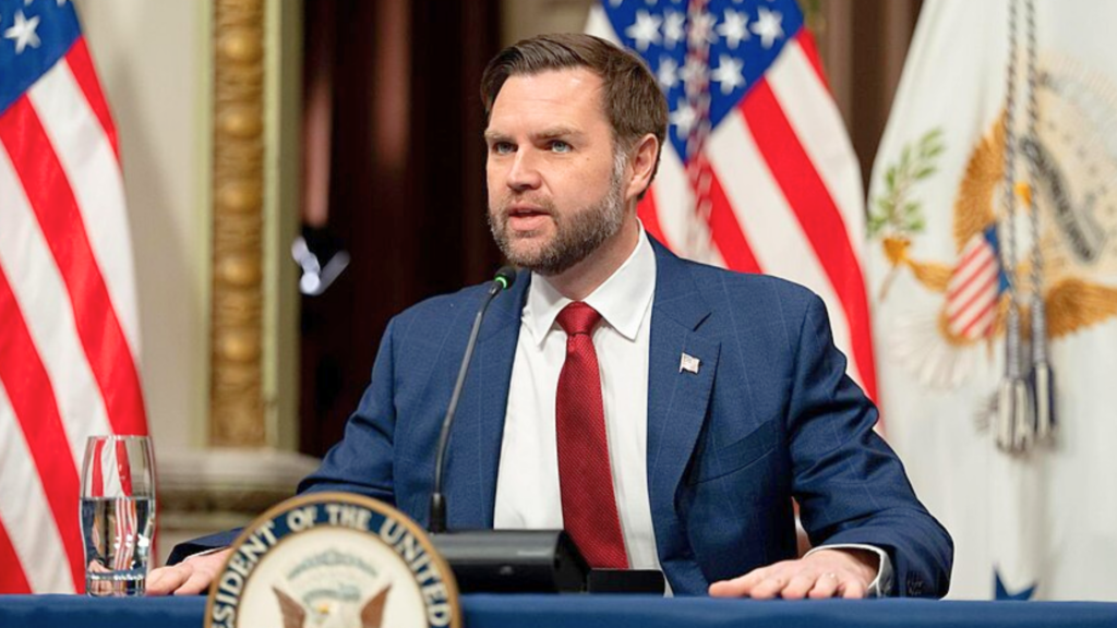 J.D. Vance speaking at a podium with United States flags in the background.