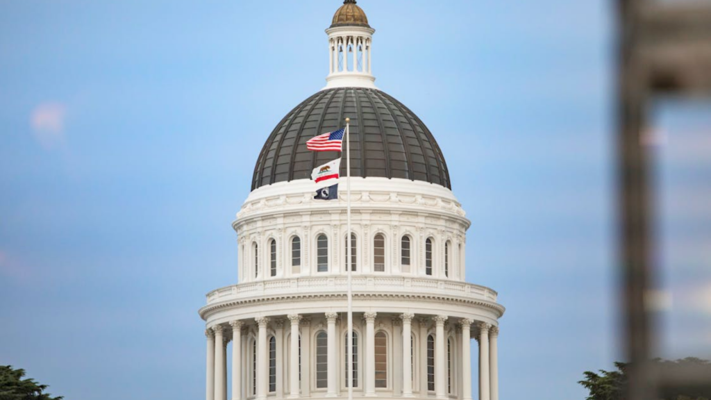 The dome of the California State Capitol building flying the US and California flags.