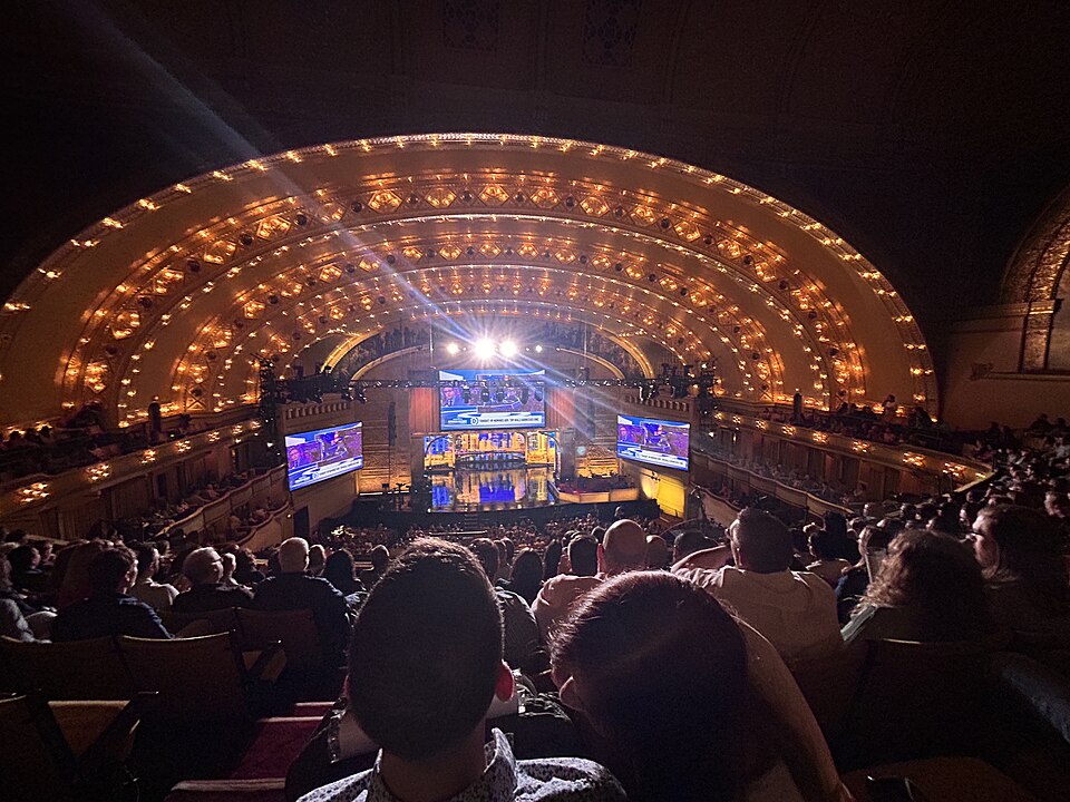 Audience members sit inside the illuminated Auditorium Theatre while watching a live taping of The Late Show with Stephen Colbert.