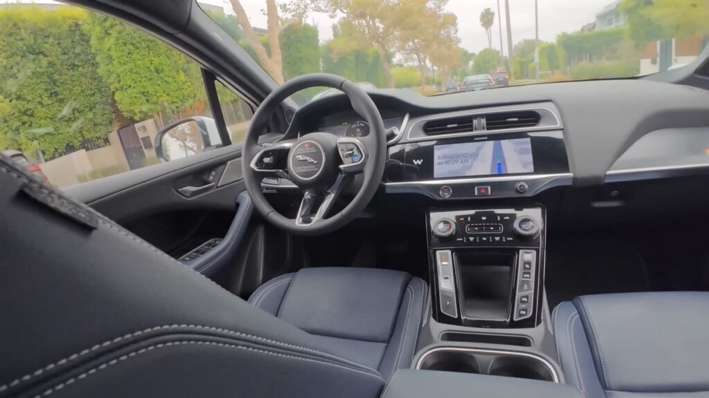 Interior of a Jaguar self-driving vehicle showing steering wheel, dashboard display, and center console.