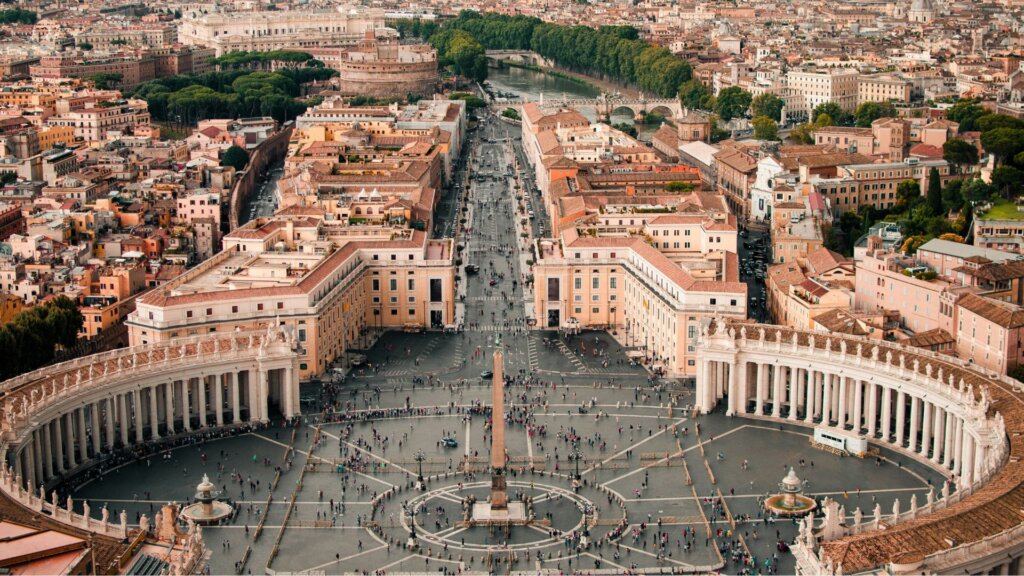 An aerial view of Vatican City, showing a broad perspective of the historic skyline and surroundings.
