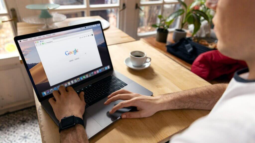 Person using laptop with Google homepage displayed on screen.
