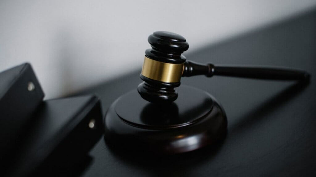 Dark wooden gavel with gold band resting on sound block.