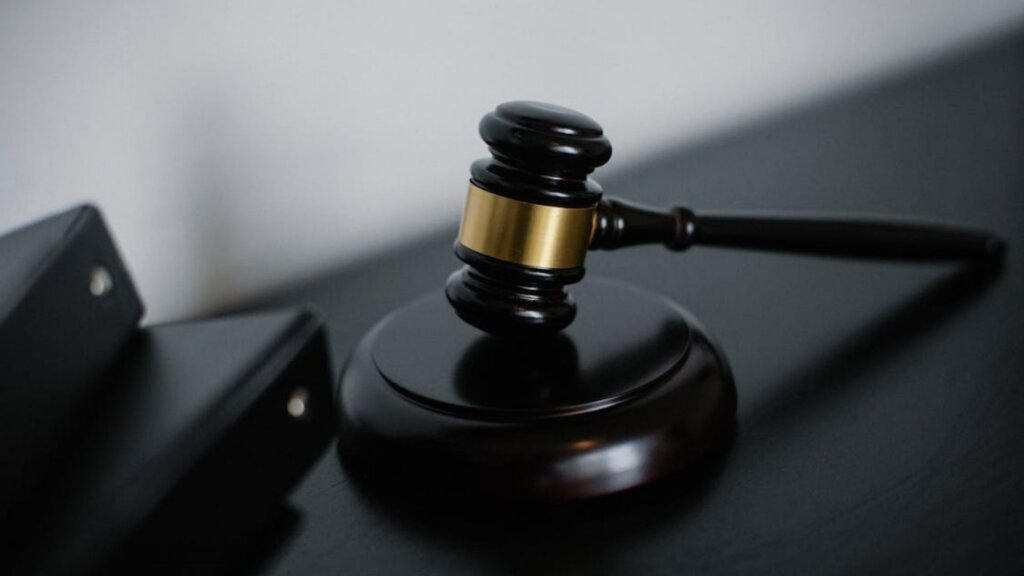 Dark wooden gavel with gold band resting on sound block.
