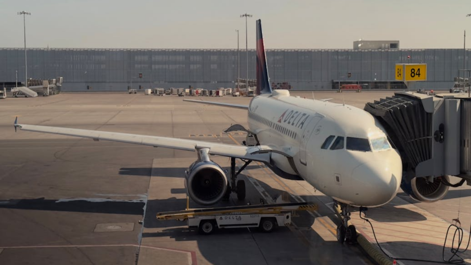 Delta Flight Returns to Gate After Passenger Refuses to End Phone Call Before Takeoff A Delta Air Lines Airbus narrowbody jet parked at airport Gate with a baggage conveyor loader positioned beneath its open cargo hold.