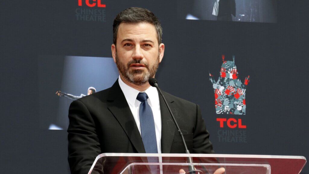 Jimmy Kimmel speaking at a podium at TCL Chinese Theatre.