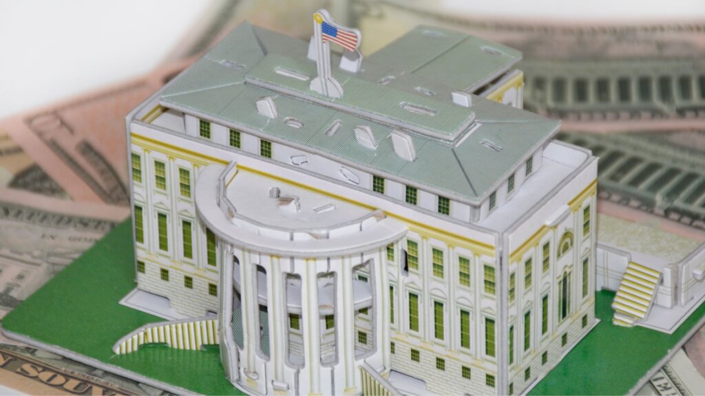 White House miniature model placed on top of US dollar bills.