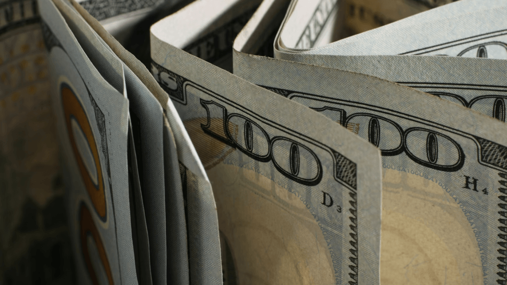 A thick stack of folded one-hundred-dollar bills viewed from an angled, top-down perspective.