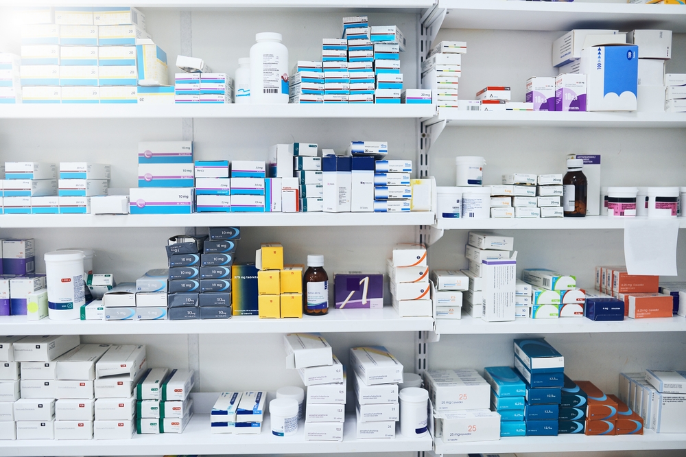 Shelves stocked with prescription medications and pharmaceutical supplies in a pharmacy.