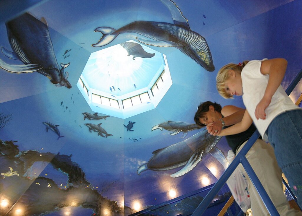 People descend stairs into the Mall at Pearl Harbor beneath a marine-life mural painted by artist Wyland.