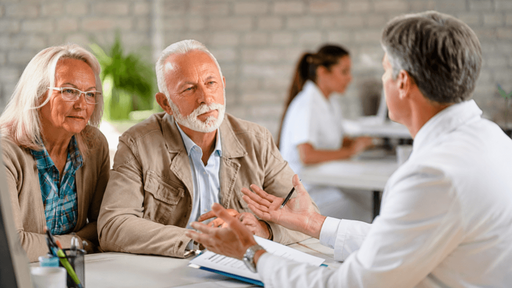 A professional gesturing during a consultation meeting with an elderly couple in an office.