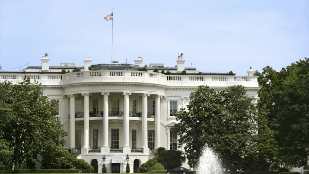 The exterior view of the White House South Portico with an American flag flying on top.
