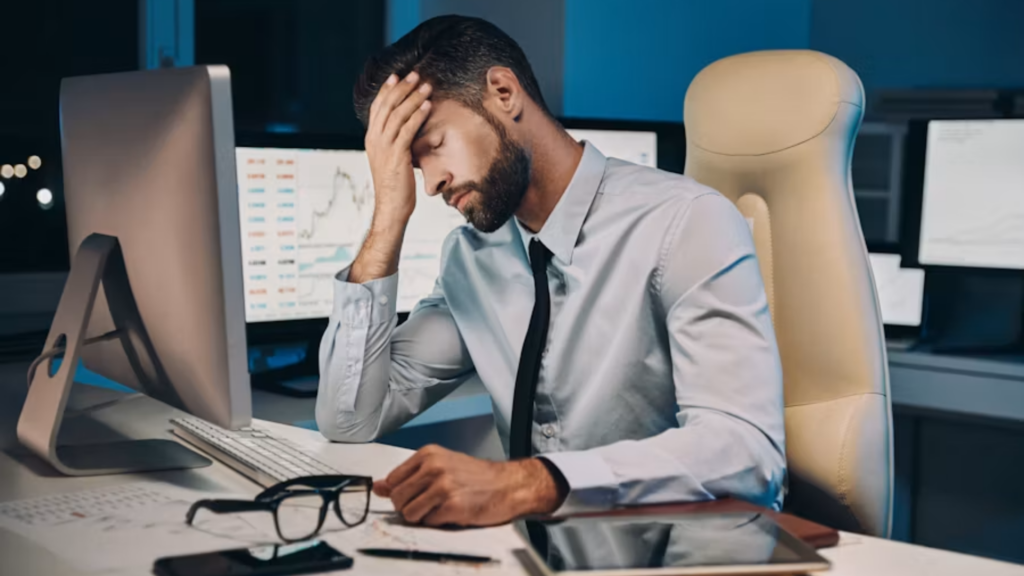 A frustrated office worker sitting at a computer, struggling with a poor internet connection and service interruptions during work.