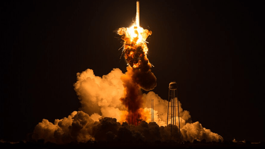 The dramatic moment a rocket suffers a catastrophic launch pad failure, disintegrating in an enormous explosion of flame and smoke against the night sky.