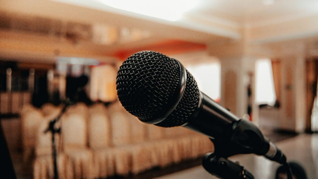 Close-up of a black microphone on a stand in an empty venue.