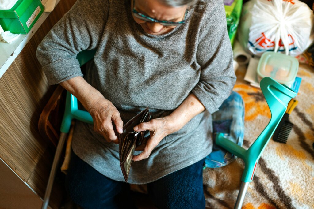 Elderly woman checking her wallet while seated at home.