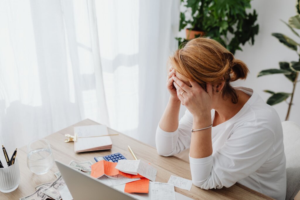 Woman reviewing bills and receipts at a desk with a laptop.