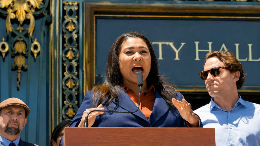 Woman speaking at a podium outside City Hall.