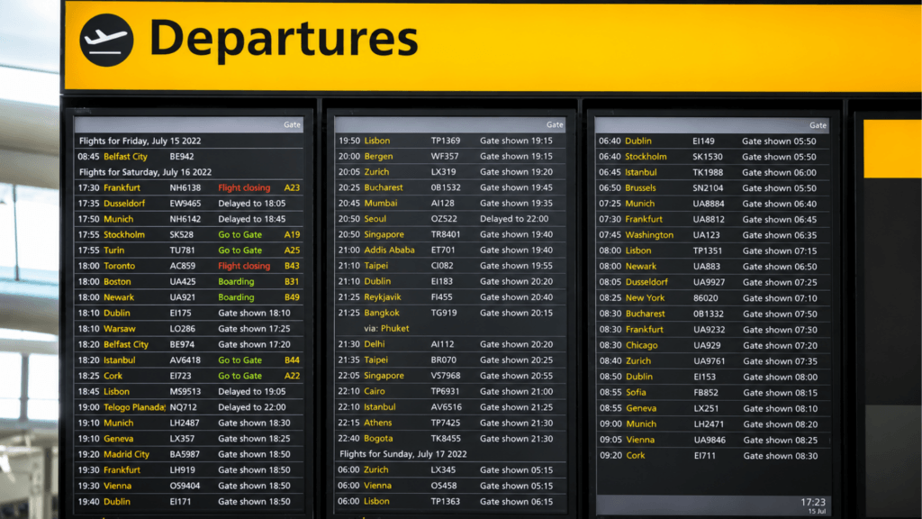 A large digital departures board inside an airport terminal displaying real-time flight schedules, destinations, and gate statuses.