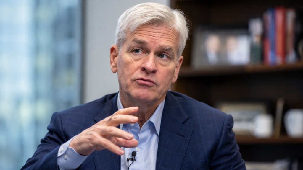 Bill Cassidy speaks during an interview in an office, gesturing with one hand while wearing a blue suit and light blue shirt.