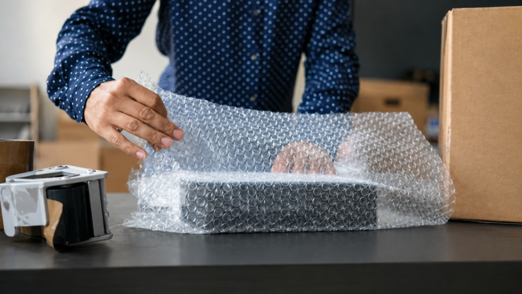 Person wrapping a package in bubble wrap for shipping.