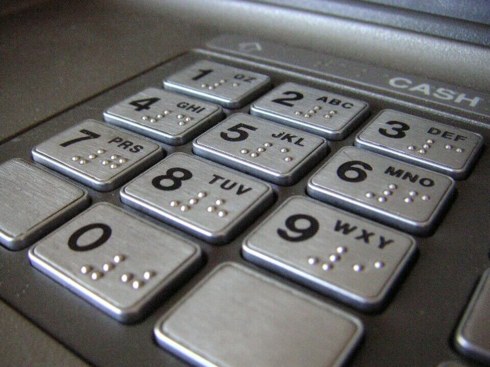 Close-up of an ATM keypad with raised Braille markings on the number buttons.