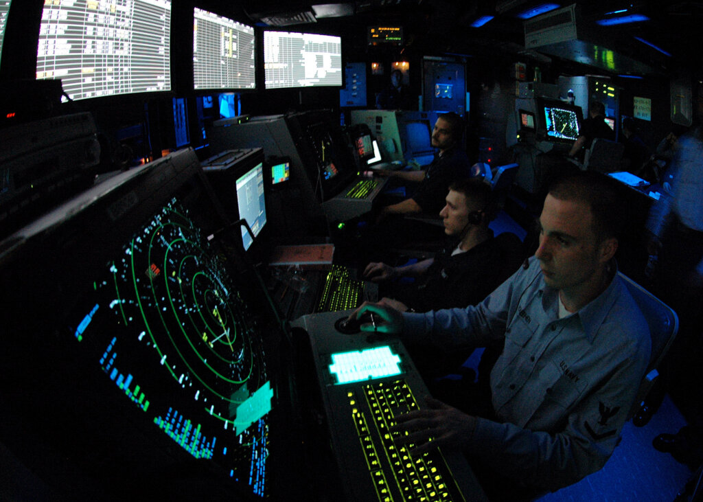 Personnel monitor radar screens and flight operations from a control center, representing the technology and coordination required to manage commercial air travel safely.