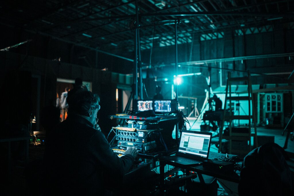 Crew members operate cameras and production equipment on a soundstage during a film or television production.