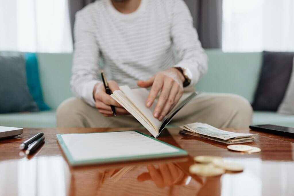 Person reviewing finances and cash at home while budgeting for student loan payments.
