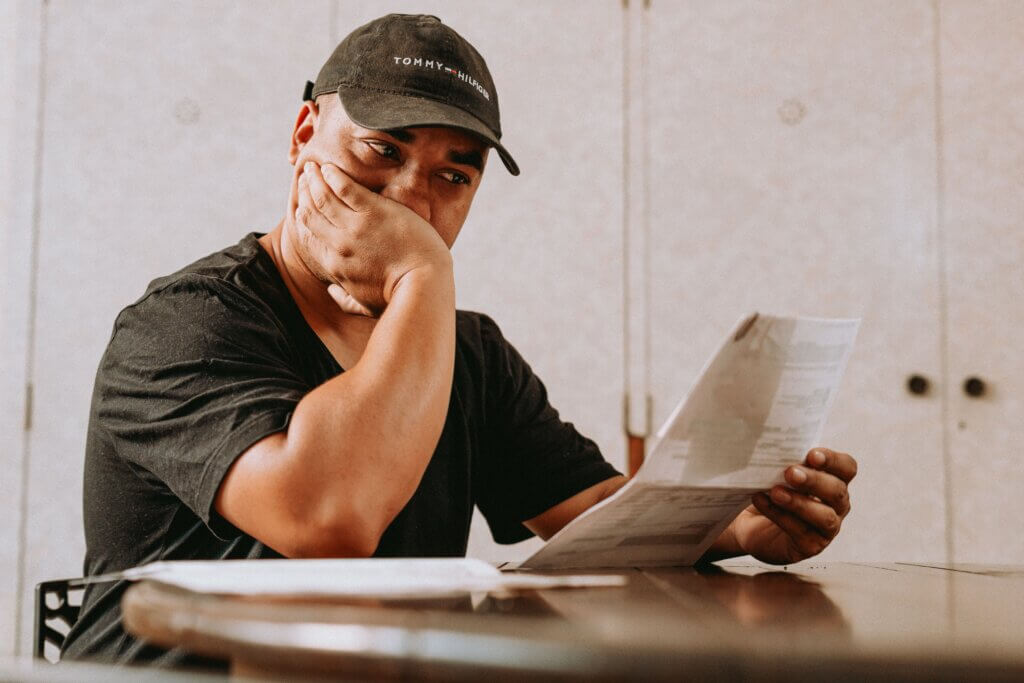 Man reviewing paperwork while seated at a table with a concerned expression.