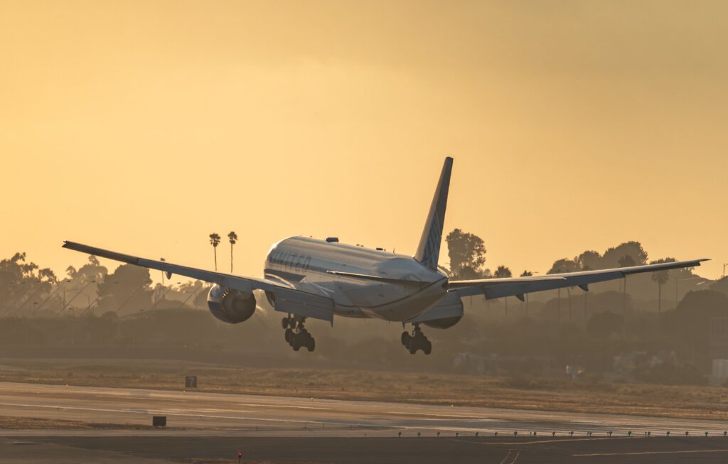 United Airlines passenger jet landing on an airport runway at sunset.