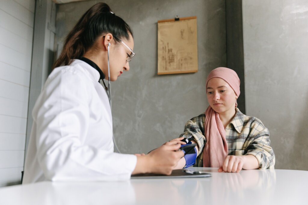 A healthcare professional measures a young patient's blood pressure during a medical appointment while the patient sits calmly in an examination room.