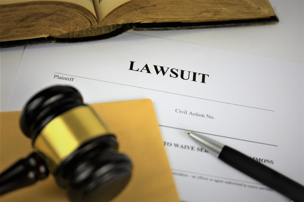 Lawsuit filing displayed with a judge's gavel, pen, and an open law book.