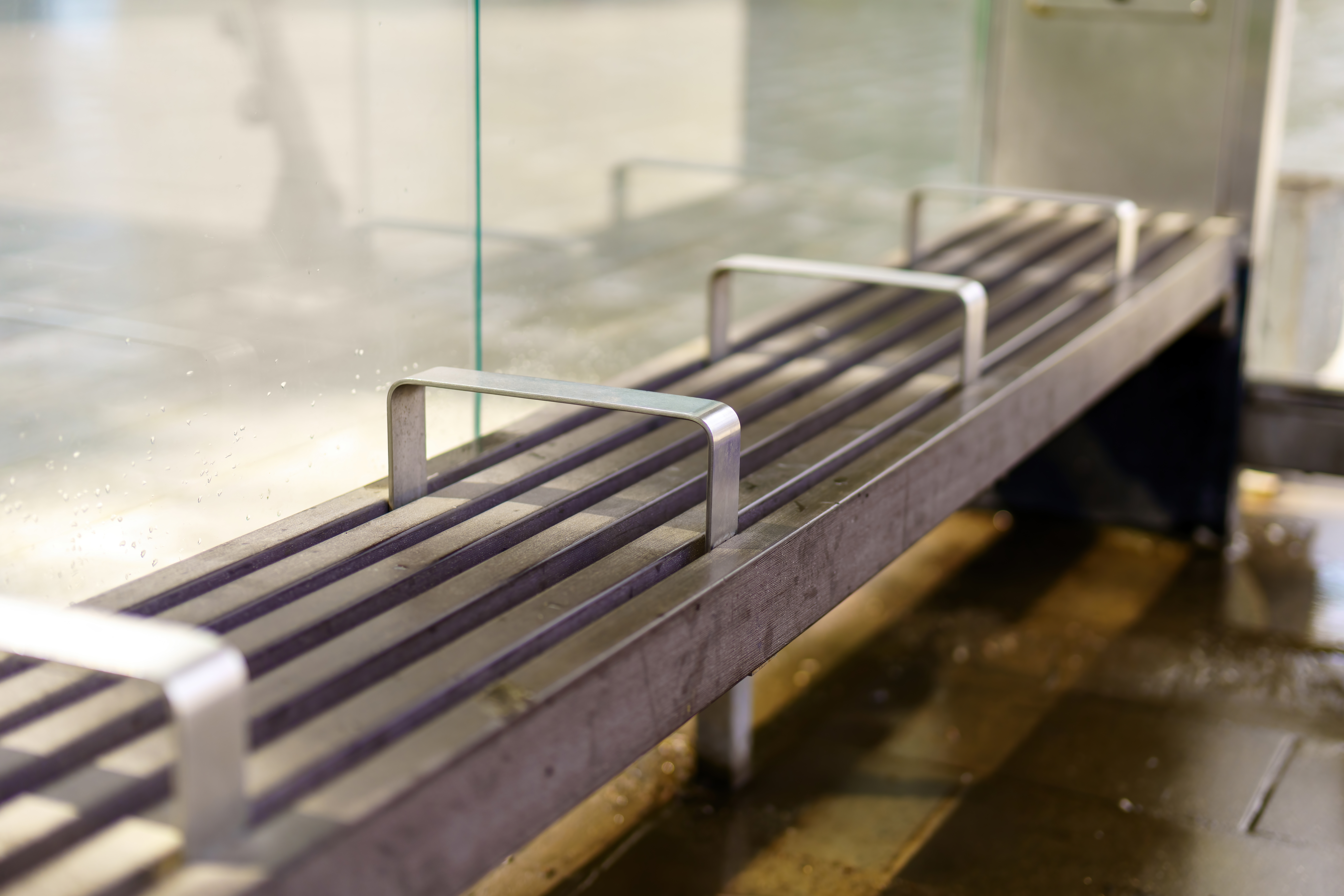 Metal public bench with evenly spaced center armrests that divide the seating into separate sections, a design often discussed in debates over hostile architecture.