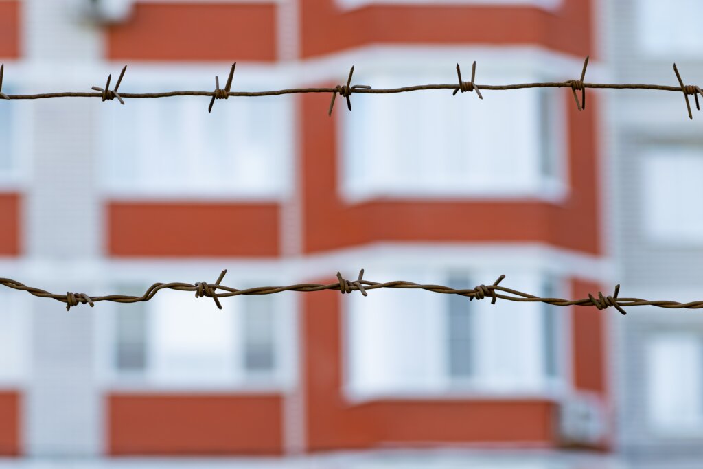 Barbed wire fence in front of a residential apartment building.