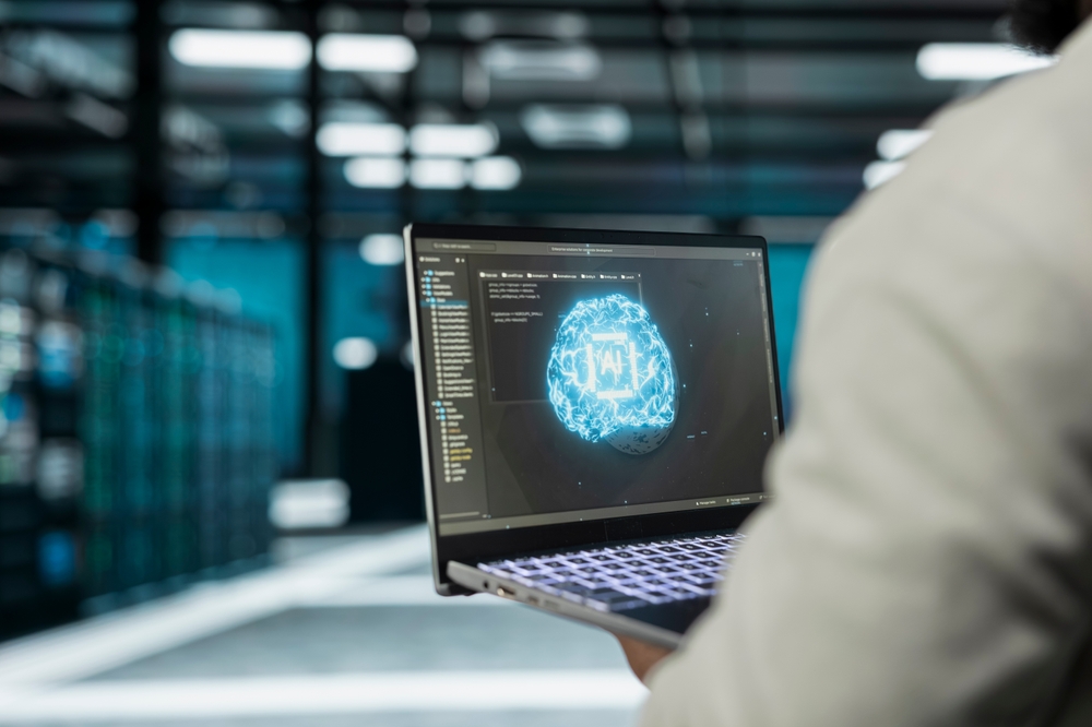 Person using a laptop displaying an artificial intelligence graphic in a data center.