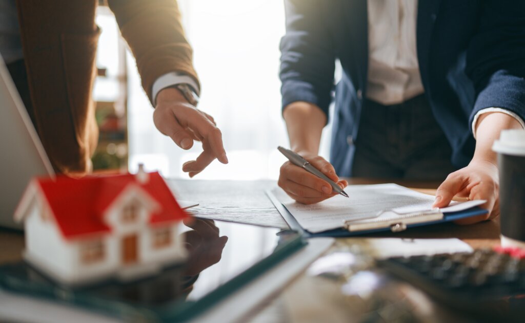 Prospective homebuyers reviewing and signing real estate documents with an agent.