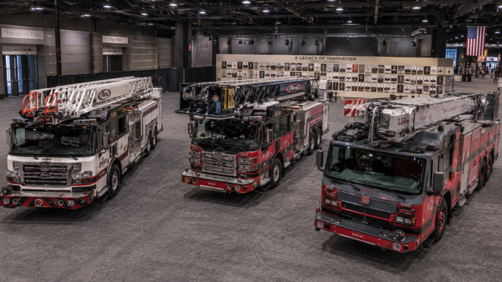 Three modern fire trucks displayed side by side inside a large exhibition hall.