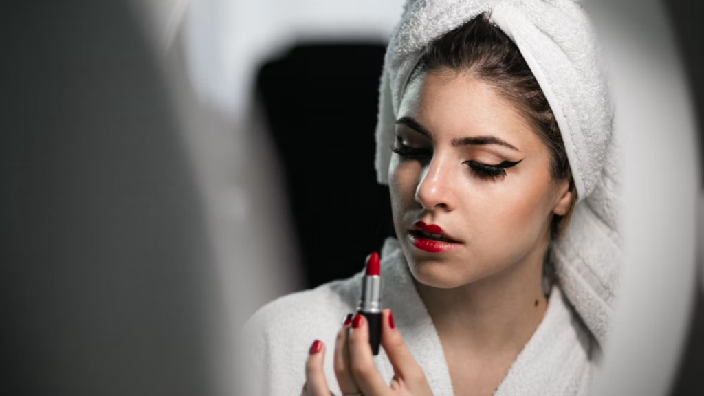A model applies deep berry-toned lipstick alongside a blended smoky eyeliner make-up.