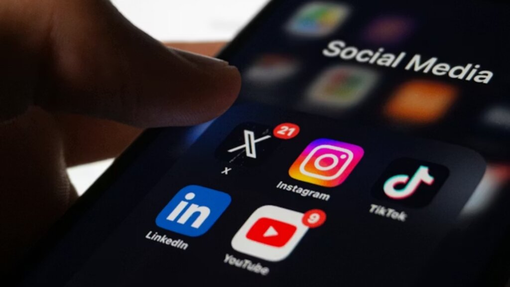 Close-up of a smartphone displaying social media apps, including Instagram, TikTok, X, LinkedIn, and YouTube.