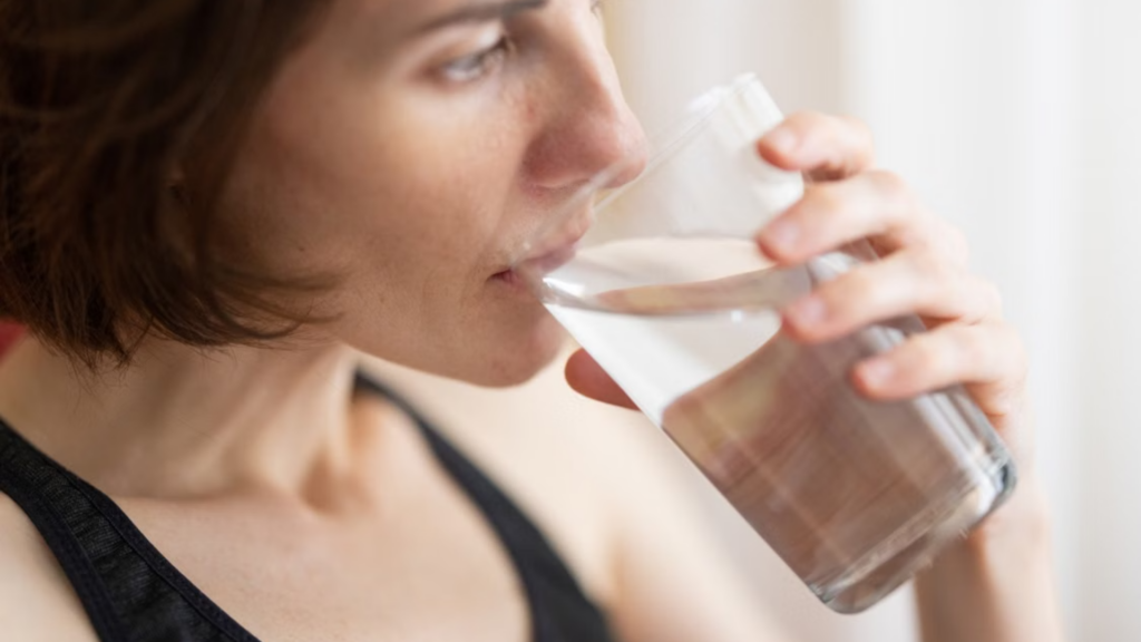 Close-up of a woman drinking water from a clear glass.