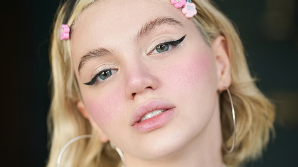 A soft cream blush into a model's cheekbone, illustrating the season's soft, monochromatic pink wash carried from cheeks to eyelids for a natural, healthy glow.