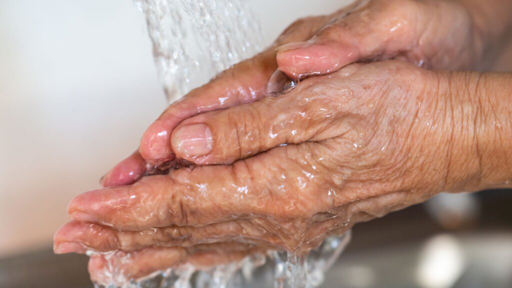 Close-up of an older adult's hands under running water.