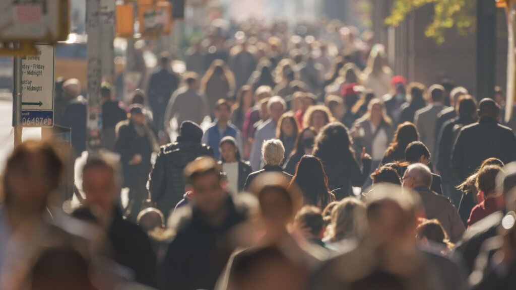 A crowd of people walking on a busy city sidewalk.