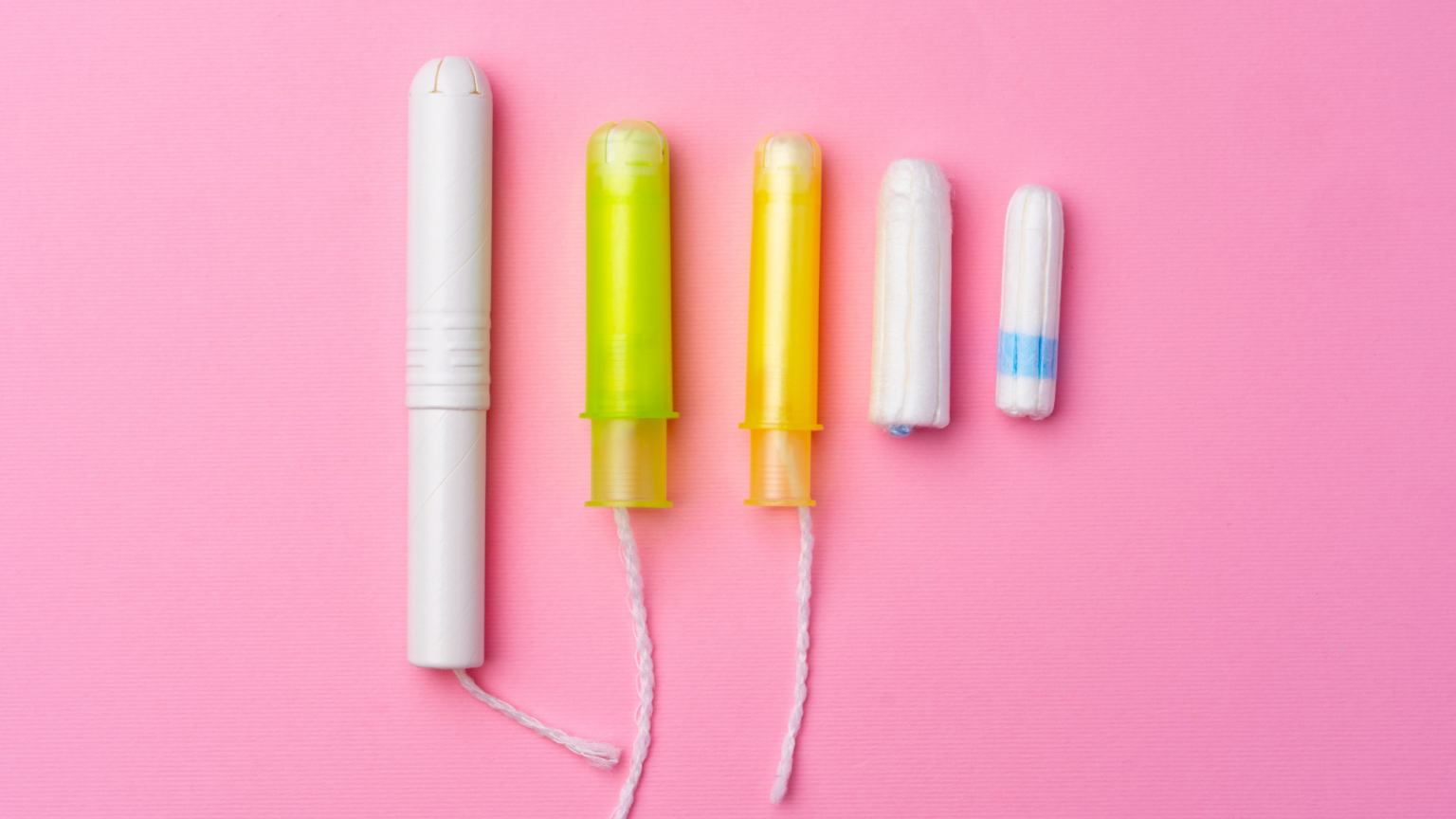 Five tampons of varying sizes, with plastic applicators and non-applicator options, arranged neatly against a bright pink background.
