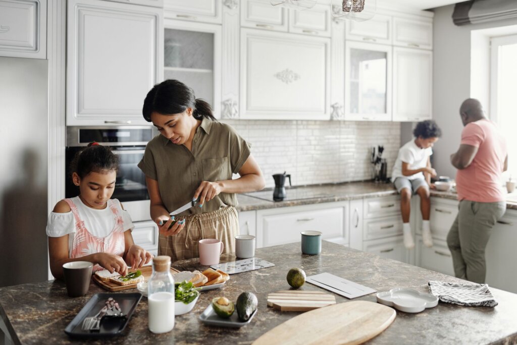 Family prepares food together around the kitchen island at home.